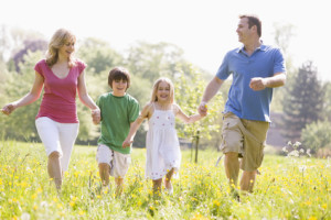 Family walking outdoors holding hands smiling